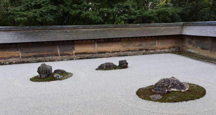 Circular compositions of stones in a contemplative raked gravel garden surrounded by earthen wall
