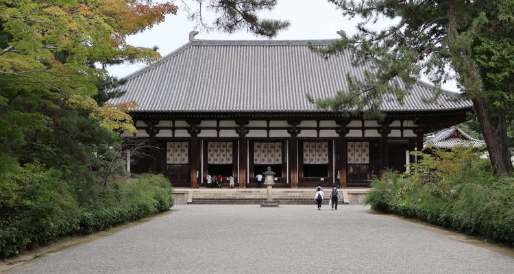 Wide gravel courtyard leading to a large wooden temple hall amid greenery
