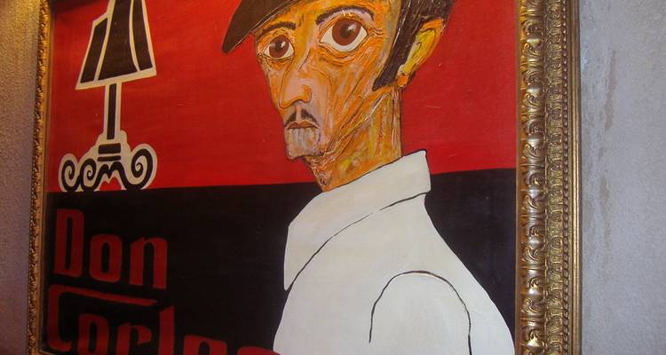 Tableau vintage encadré intitulé « Don Carlo » exposé sur un mur texturé à l'intérieur d'un bar sicilien.