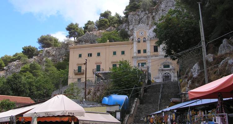 Résidence historique sur une colline avec tour d'horloge dominant les étalages du marché et les falaises rocheuses.