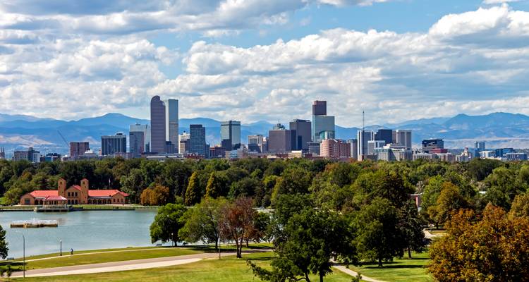 El horizonte de Denver elevándose sobre el lago City Park con las Montañas Rocallosas a lo lejos