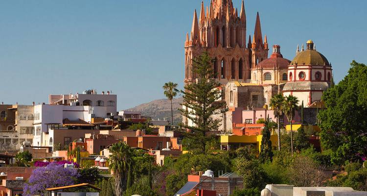 Vue panoramique de San Miguel de Allende avec son église aux flèches roses emblématique s'élevant au-dessus des maisons coloniales colorées.