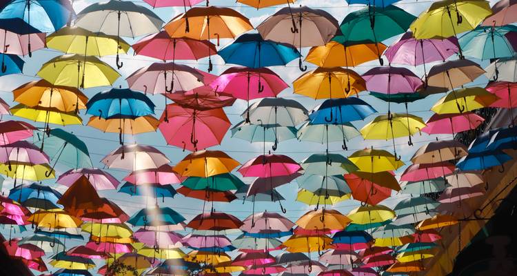 Canopée de parapluies colorés flottant au-dessus d'une ruelle mexicaine étroite