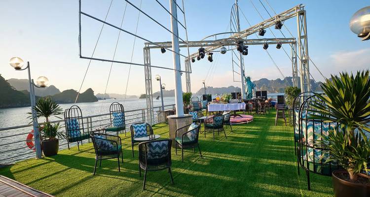 Open-air sundeck on a cruise ship with green turf, seating, and views of Halong Bay’s limestone peaks.