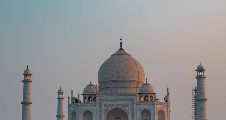 De marmeren koepel en minaretten van de Taj Mahal rijzen op tegen een pastelkleurige dageraadhemel.