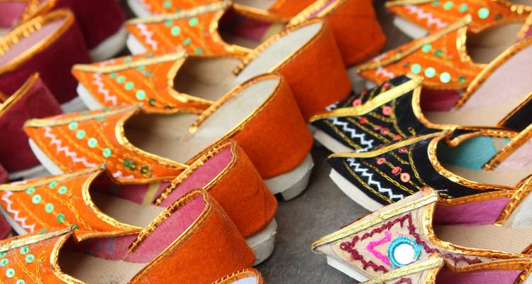Felgekleurde geborduurde Rajasthanische schoenen gestapeld in een levendige marktuitstalling.