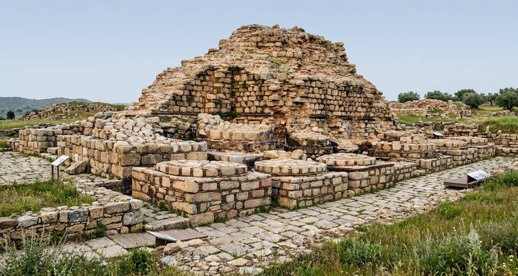 Stenen ruïnes van een oud Boeddhistisch kloosterkomplex in Taxila onder een bleek blauwe hemel.