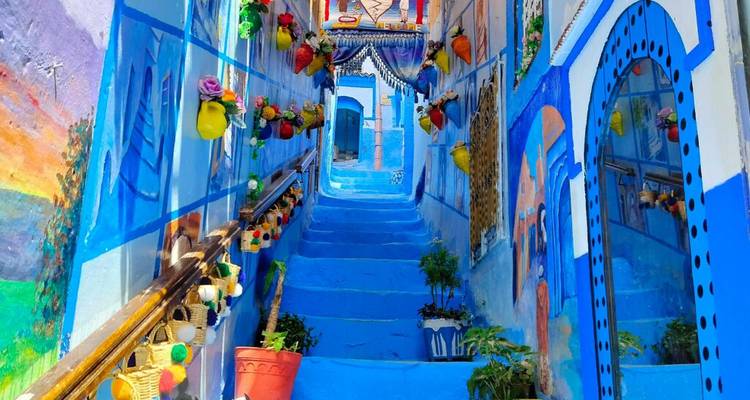 Escalera pintada de un azul vibrante decorada con flores y adornos en la medina de Chefchaouen.