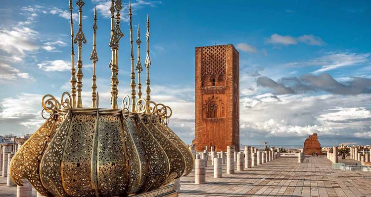 Torre Hassan y lámpara de bronce decorativa en el complejo de mausoleos de Rabat bajo un cielo azul brillante.