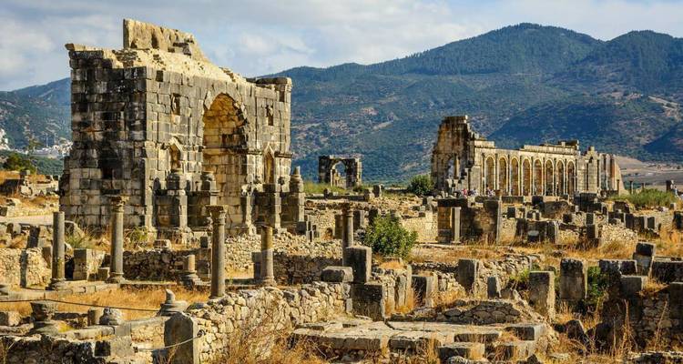 Amplias ruinas romanas de Volubilis rodeadas de colinas y montañas ondulantes de Marruecos.