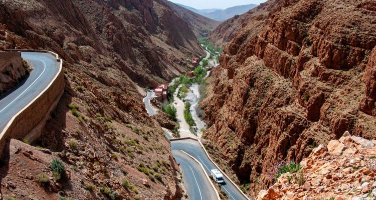 La sinuosa carretera de montaña serpentea a través de los acantilados rojos y gigantescos de la Garganta de Todra con el río abajo.