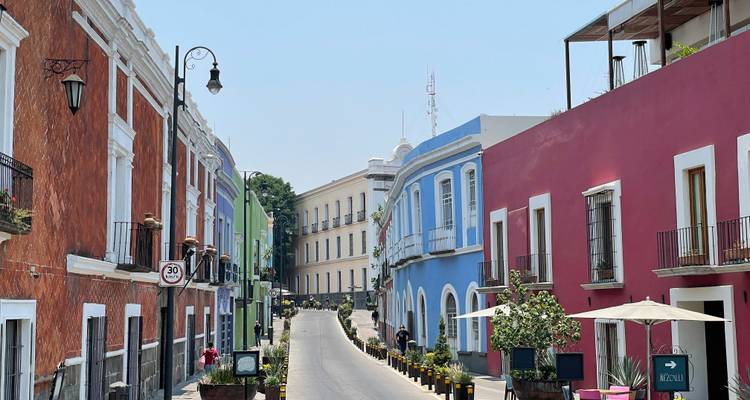 Charmante Kopfsteinpflasterstrasse, gesäumt von leuchtend bemalten Kolonialhäusern in Puebla unter klarem Himmel.