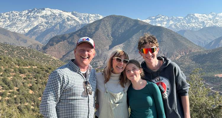 Familia sonriente posando con las nevadas montañas del Atlas de fondo.