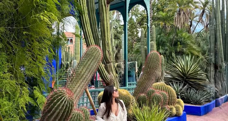 Mujer rodeada de cactus imponentes y exuberante vegetación dentro del Jardín Majorelle de Marrakech.
