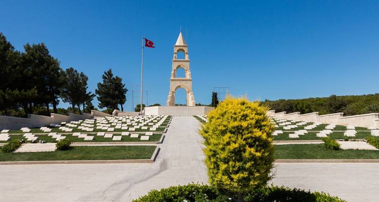 Nette militaire begraafplaats met witte grafstenen die naar een hoog gedenktoren en de Turkse vlag leiden.