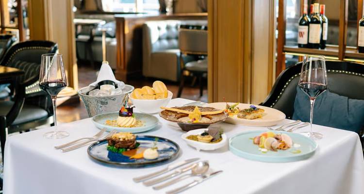 Elegant table setting with gourmet dishes and wine glasses inside a refined ship restaurant
