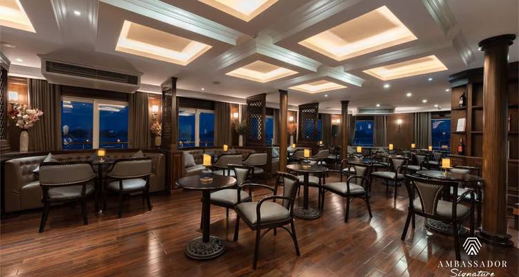 Stylish lounge with leather chairs and wooden floors illuminated by ceiling coffers