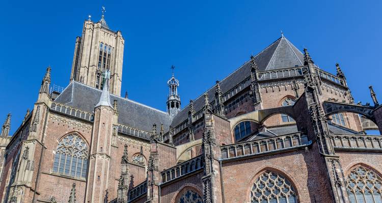 Detailed brick and stone façade of a Gothic cathedral against a deep blue sky in Arnhem.