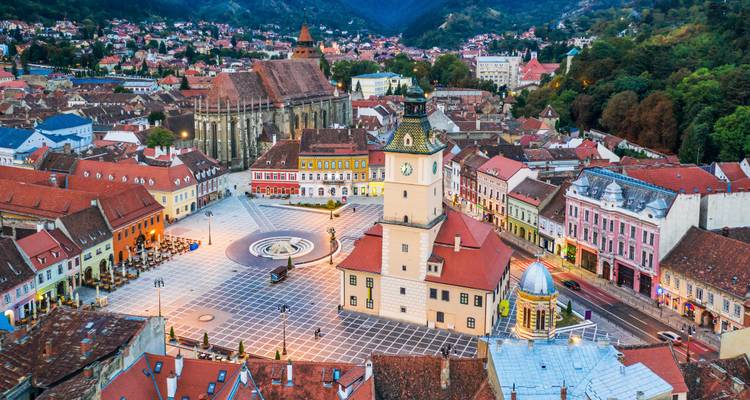 Vista aérea con dron de la Plaza del Consejo de Brasov con torre del reloj, Iglesia Negra y las colinas de los Cárpatos circundantes.
