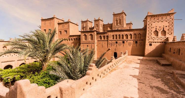 Les tours en terre et les motifs géométriques complexes d'Aït Benhaddou brillent sous un ciel désertique chaleureux.
