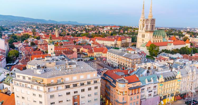 Aerial panorama of Zagreb with its twin-spired cathedral and red-roofed old town at dusk.