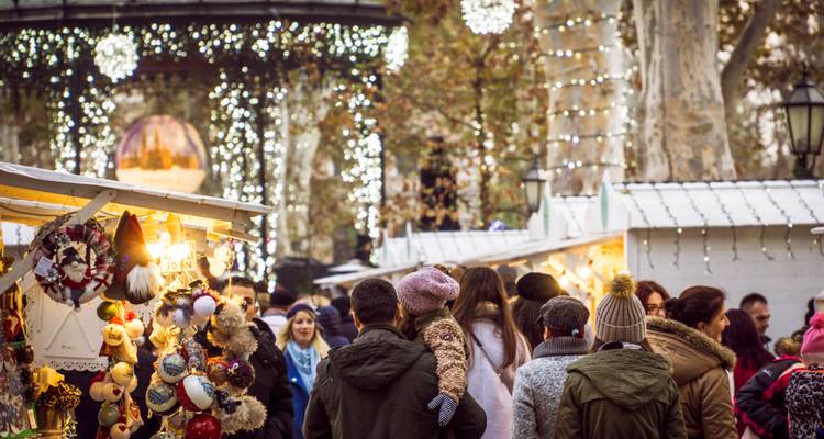 Festive Christmas market stalls in Zagreb illuminated with twinkling lights and crowds browsing decorations.