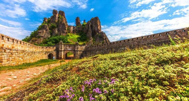 Belogradchik Fortress-muren die naar imposante rode rotsformaties onder een heldere hemel leiden.