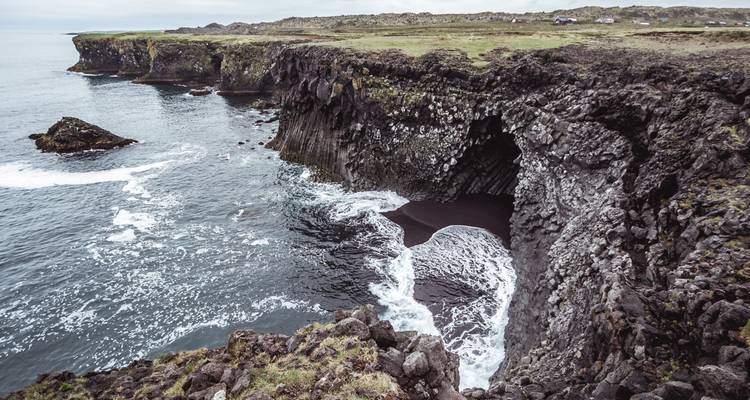 Les falaises de basalte et une grotte marine rencontrent les vagues écumantes de l'Atlantique le long d'une côte accidentée.