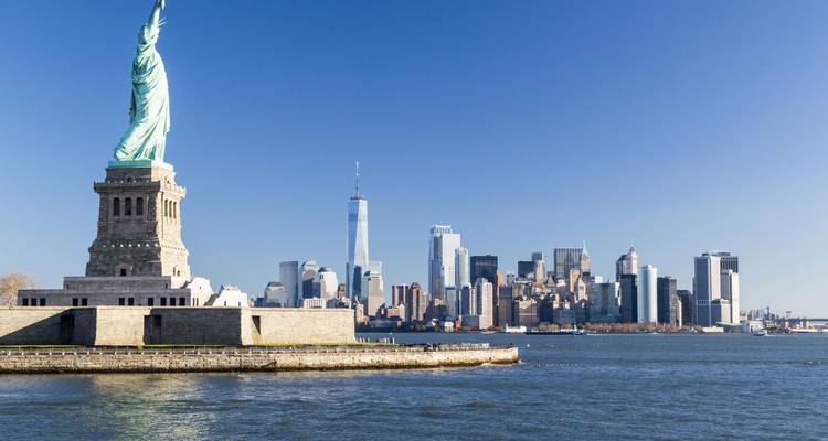 La Estatua de la Libertad se alza frente al horizonte de la Ciudad de Nueva York en un día despejado y sin nubes.