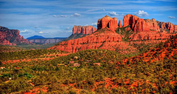 Les formations rocheuses rouges spectaculaires s'élèvent au-dessus des forêts verdoyantes sous un ciel bleu éclatant à Sedona