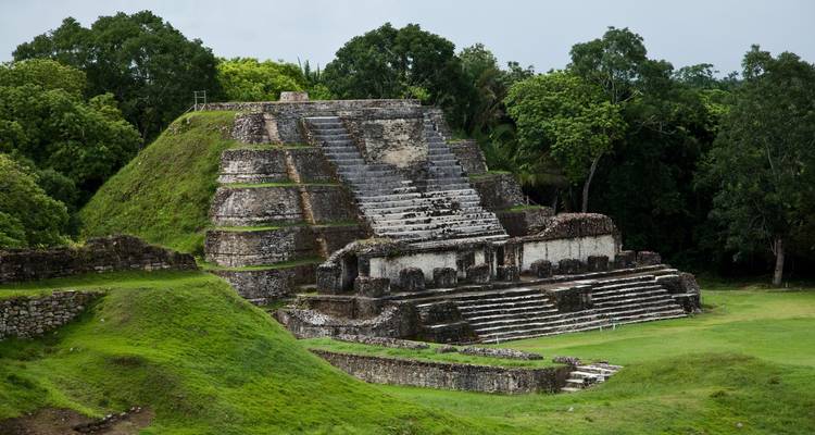 Impressionnante pyramide maya à degrés s'élevant d'un environnement verdoyant luxuriant sous un ciel couvert.