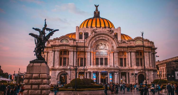 Sonnenuntergangsblick auf den Palacio de Bellas Artes in Mexiko-Stadt mit Menschenmengen auf dem Platz und einem rosa Himmel