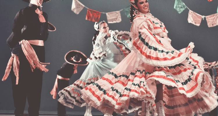 Weibliche Tänzerinnen in farbenfrohen mehrschichtigen Kleidern, die sich während einer traditionellen mexikanischen Folkloreveranstaltung drehen
