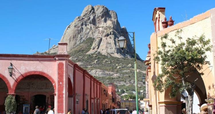 Village street with colorful colonial arches leading toward the imposing Peña de Bernal rock