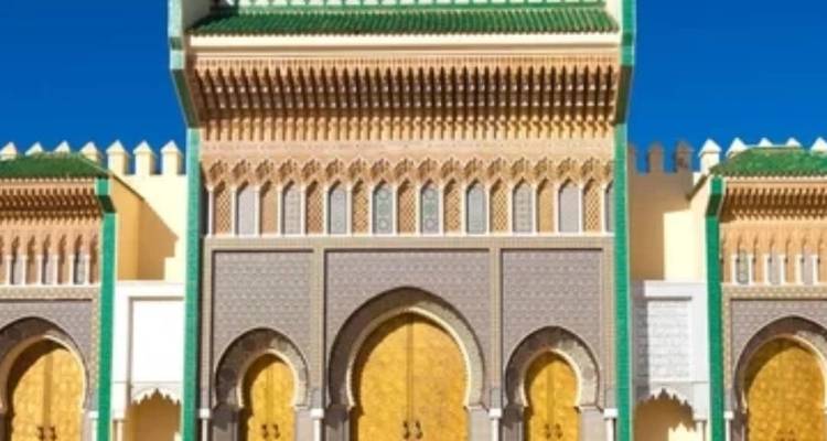 Puerta ornamentada de colores brillantes del Palacio Real en Fez con techo de azulejos verdes y puertas doradas bajo un cielo azul.