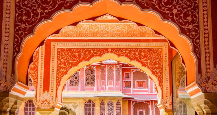 Die kunstvoll verzierten orange- und rotfarbenen Bögen des City Palace von Jaipur rahmen sich gegenseitig perspektivisch ein.
