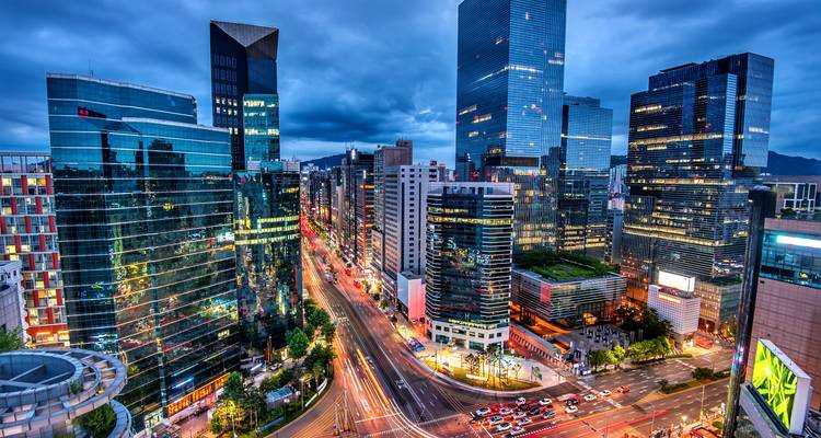 Vibrant dusk cityscape of Seoul’s skyscrapers with traffic trails illuminating broad avenues.