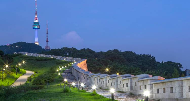 Die beleuchtete Festungsmauer verläuft zur blauen Stunde in Kurven auf den N Seoul Tower zu.