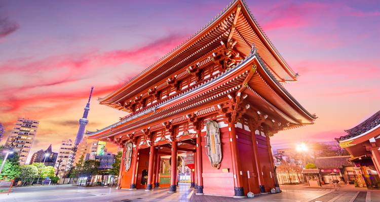 La puerta del templo Senso-ji iluminada al atardecer con la Tokyo Skytree y el cielo teñido de rosa de fondo.