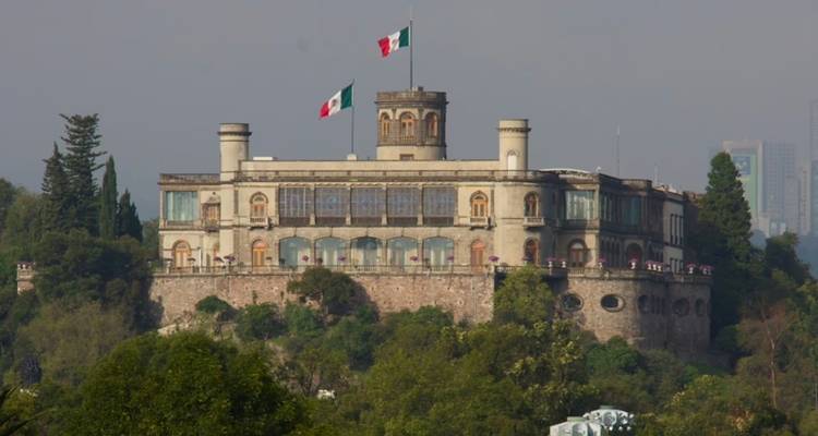 Das Schloss Chapultepec mit zwei mexikanischen Flaggen gekrönt, das sich über einen bewaldeten Hügel in Mexiko-Stadt erhebt