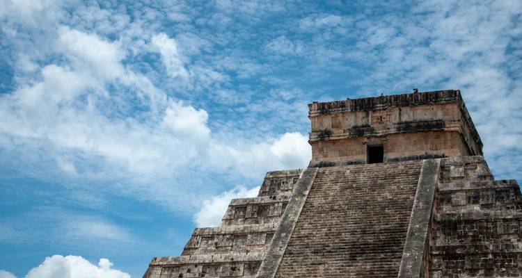 La pyramide à degrés en pierre s'élève vers un ciel bleu éclatant rempli de nuages dispersés.