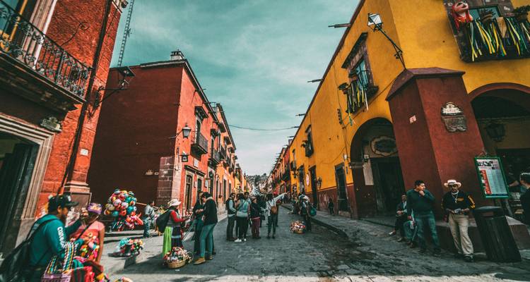 Rue coloniale colorée bordée de façades jaunes et rouges animée par les piétons et les vendeurs de rue.