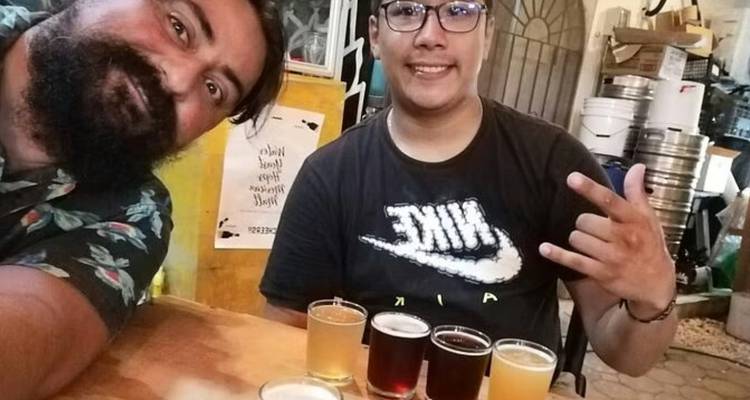 Selfie von zwei jungen Männern, die lächeln, mit einem Bierflug auf dem Tisch in einer zwanglosen Bar.