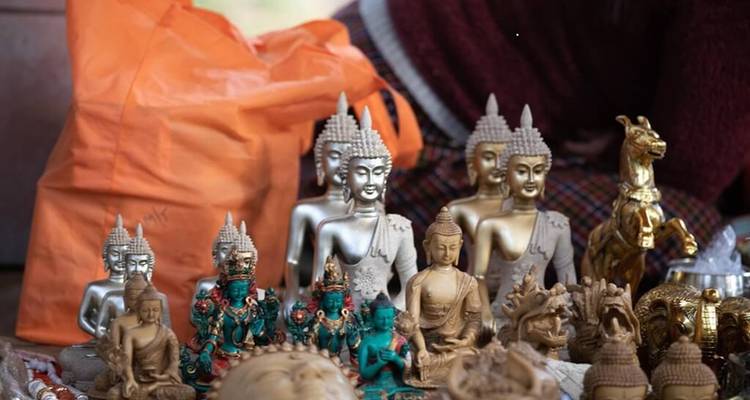 Assortiment de petites figurines de Bouddha et de souvenirs religieux exposés sur une table de marché.
