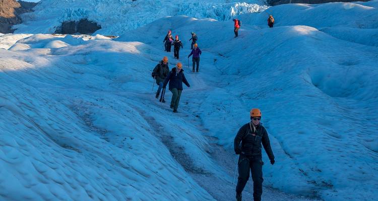Avonturengroep met helmen trekking over een blauw gletsjeroberflak