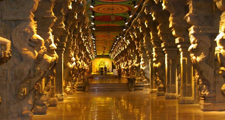 Corridor à colonnades ornementales à l'intérieur du temple Meenakshi, richement sculpté et éclairé d'une lumière dorée chaleureuse.