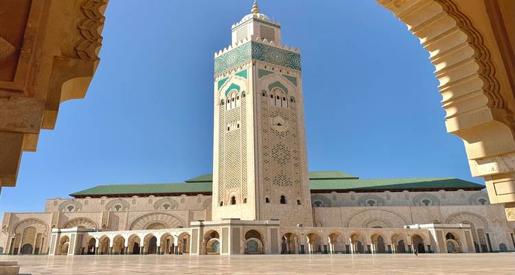 La Mosquée Hassan II encadrée par des portiques ornés sous un ciel bleu parfait.