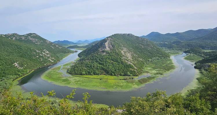 Ikonische S-förmige Flussschleife, die sich durch üppig grüne Berge unter klarem Himmel windet