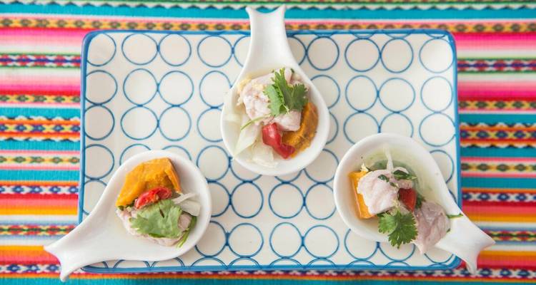 Assiette de dégustation péruvienne colorée avec trois cuillères en céramique de ceviche sur tissu à motifs