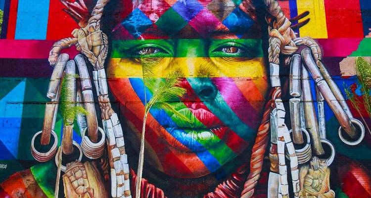 Vivid urban mural depicting a multicoloured indigenous face with intricate detail.